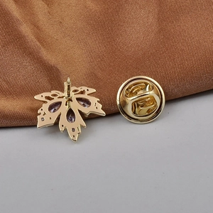 Golden maple leaf brooch with purple zircon, including back pins on brown silk