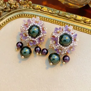 Vintage floral pearl drop earrings with purple flowers and green pearls in a gold tray