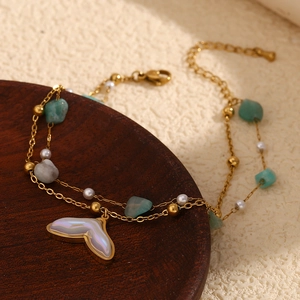 Macro detail of gold double-layer anklet with natural turquoise and white fishtail charm