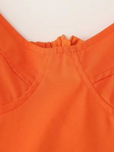 Detailopname van de oranje jurkhals met getextureerde stof en bijpassende ritsdetail