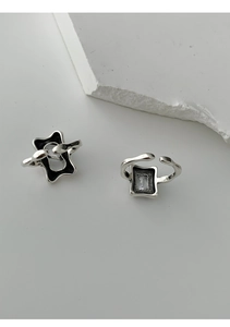 Macro detail of geometric silver 925 rings with square gems on textured stone