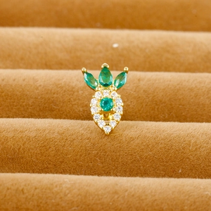 Macro shot of gold pineapple stud earrings with green and white zircons on brown velvet