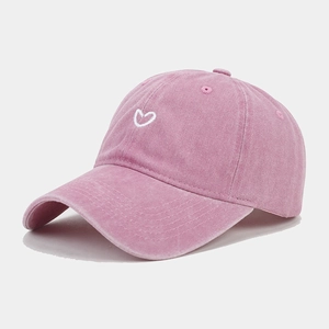 Detail view of washed pink cotton baseball cap with white heart embroidery