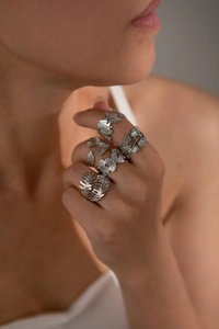 Detailed view of silver butterfly and leaf rings with hollow engraving on model fingers