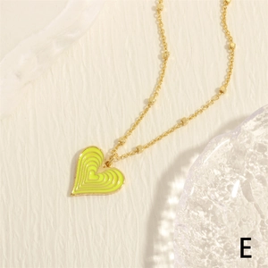 Macro detail of heart pendant with yellow enamel inlay and gold bead chain accessory
