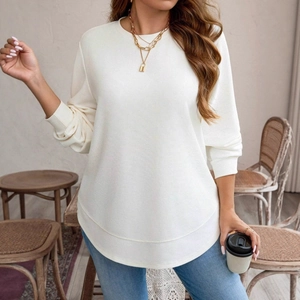 Detailed view of white waffle knit texture and curved hem on a women's long sleeve top
