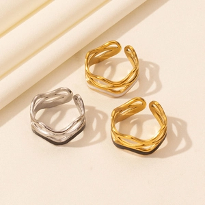 Detail of gold and silver irregular wave hollow rings on textured beige fabric