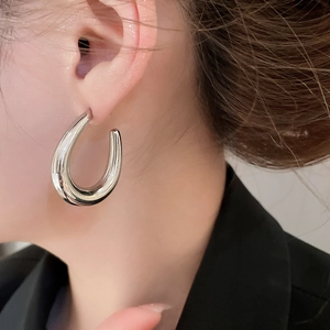Close-up of polished silver U-shaped earrings worn to show the glossy mirror finish