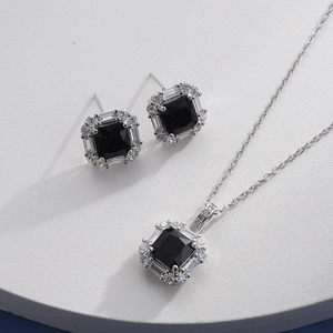 Macro detail of silver necklace and earrings set with black square zircon stones