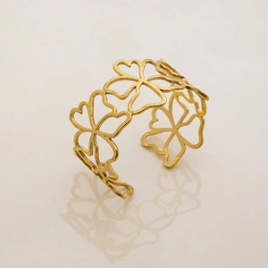 Detailed macro view of 18K gold plated stainless steel open bangle with hollow flower patterns