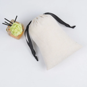 Top view of a beige canvas drawstring jewelry bag with black cords on white background