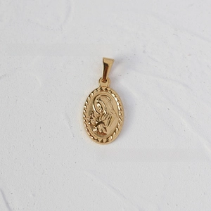 Macro detail of golden oval religious relief pendant on textured white stone background