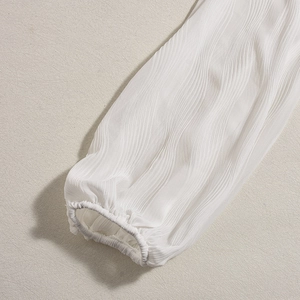 Detailed macro shot of white pleated fabric texture and elastic cuff on lantern sleeve
