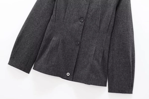 Detailaufnahme des dunkelgrauen Blazer-Stoffs mit schwarzen Knöpfen und feinen Nähten