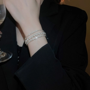 Detail of multi-layer silver bracelet with white pearls and sparkling rhinestones