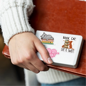 Close-up of cute cartoon cat and book stickers applied on a white portable device