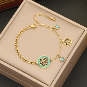 Detail of tree of life charm and turquoise bead on gold-tone bracelet with lobster clasp