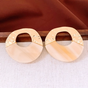 Detail of round hollow acrylic and hammered metal earrings in cream and gold