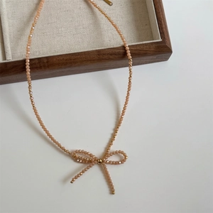 Detailed view of handmade bow pendant necklace with champagne crystal faceted beads