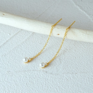 Detail shot of 925 silver gold pearl tassel earrings with zircons on wooden stand