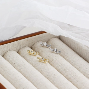 Detailed close-up of gold and silver S925 curved bubble zircon stud earrings in a jewelry box