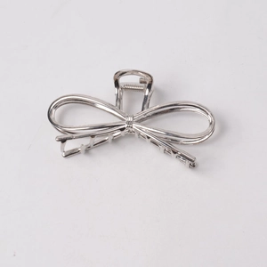 Detail showing the silver metal bow hair claw clip with a minimalist spring mechanism