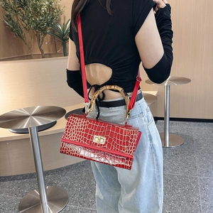 Detail of red crocodile pattern bag with bamboo handle and adjustable shoulder strap