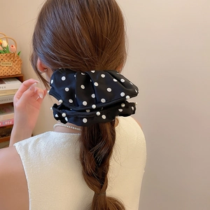 Rear view of a model wearing a black polka dot scrunchie with pearls in a French braid hair