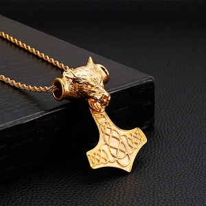 Détail d'un pendentif loup viking doré avec marteau de Thor Mjolnir sur coffret noir