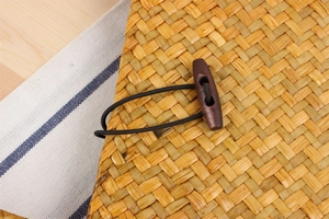 Detailed view of handmade woven straw bag with dark wooden toggle button and elastic closure
