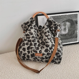 Détail du sac en peluche léopard avec poignée tissée orange sur surface textile blanche