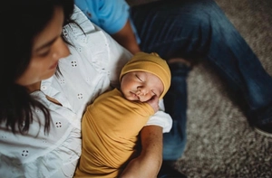 Close-up of a sleeping newborn in a ginger yellow soft knit swaddle blanket and matching hat