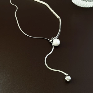 Close-up of silver snake chain necklace featuring a white pearl and metallic bead pendant