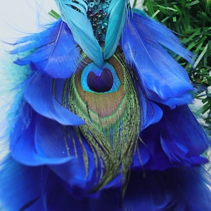 Détail d'une décoration en plumes de paon bleues avec paillettes sur sapin de Noël