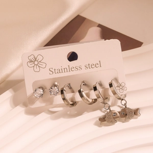 Close-up of stainless steel earring set featuring zircon studs and fish charms on a card