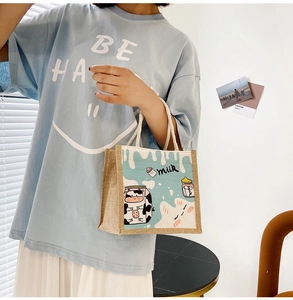 Detailed side view of a small canvas tote bag featuring cute cartoon cow and milk patterns