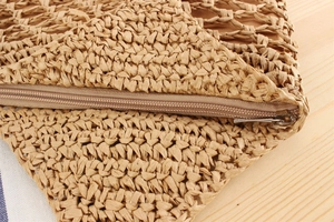 Macro view of woven straw bag texture with a metal zipper and detailed stitching