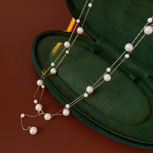 Detail of French vintage pearl necklace with gold chain on luxury green velvet box