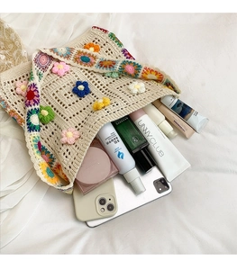 Detail view of large capacity beige crochet bag with colorful 3D flowers and accessories