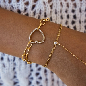 Bracelet doré de luxe avec breloque cœur et cristaux scintillants porté au poignet