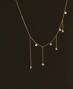 Close-up of golden tassel necklace featuring sparkling zircon pendants on a dark background