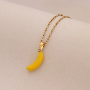 Vista macro dettagliata di una catena dorata con un piccolo ciondolo a forma di banana gialla