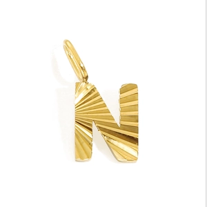 Detail of golden stainless steel letter N pendant with radial sunburst texture and ring
