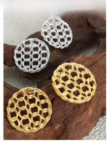 Macro detail of hollow chain disc earrings in gold and silver finish on natural wood