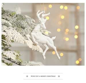 White reindeer Christmas tree ornament with glitter finish on a snowy branch
