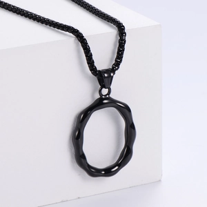 Détail macro d'un collier en acier inoxydable noir mat avec pendentif anneau irrégulier