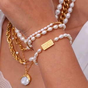 Detail of pearl bracelet with engraved golden 11:11 plate layered on wrist