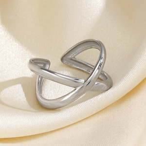 Polished silver stainless steel X-shaped crossover open ring on elegant silk background