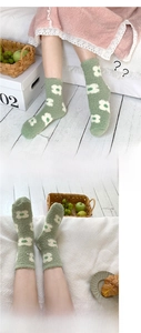 Detail of soft green coral fleece socks with white floral patterns and plush texture