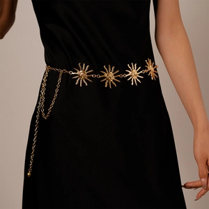 Detailed close-up of golden sun-face charms and draping chain on a metallic waist belt